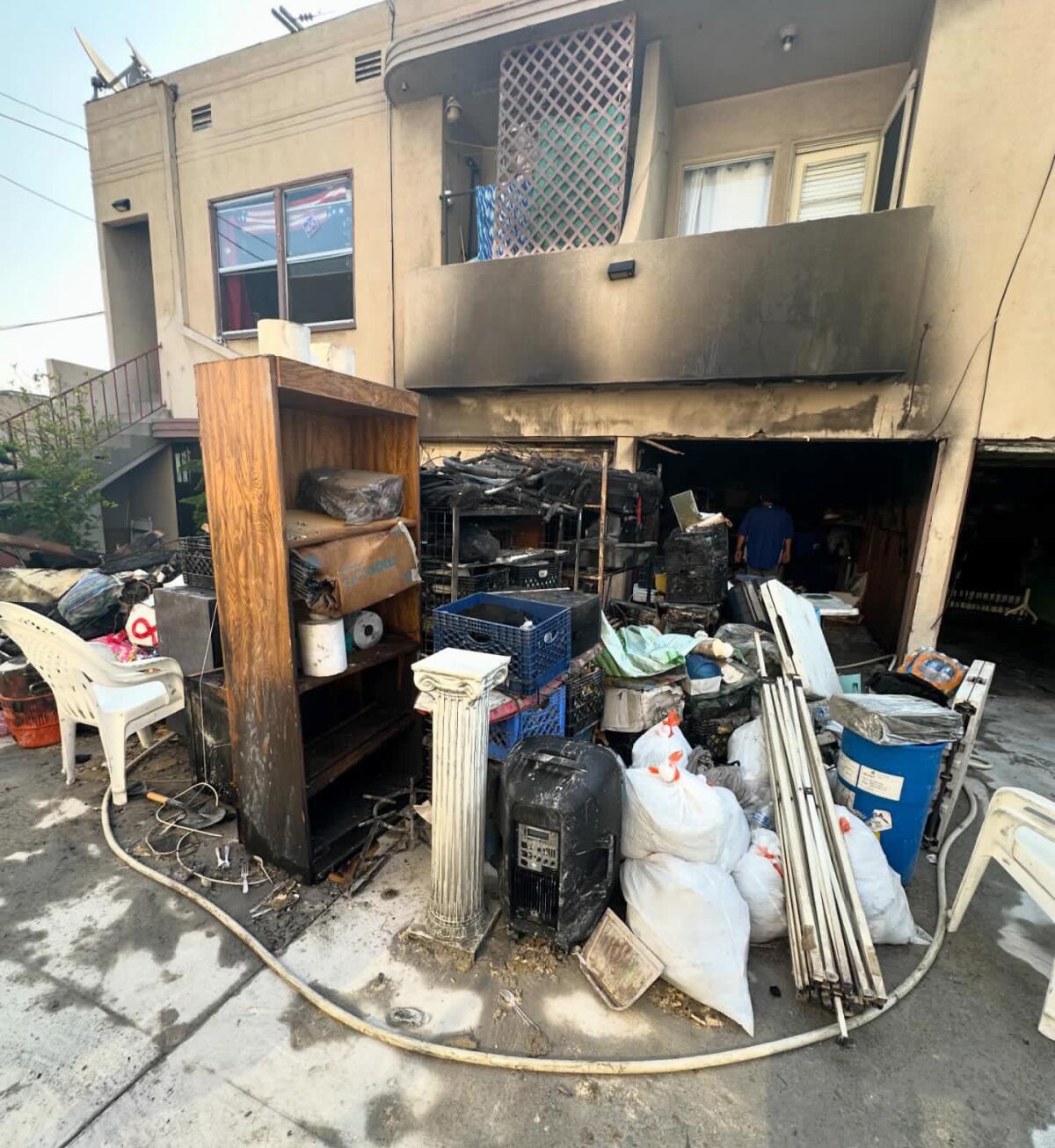 Household objects stand outside a burned building with apartments over garages.