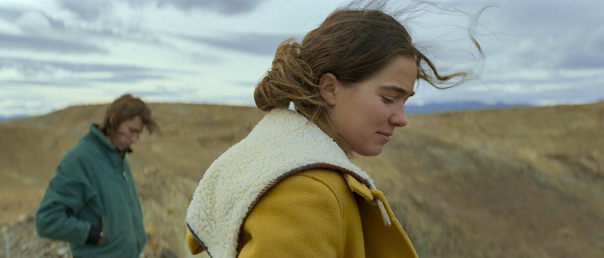 A young man and a woman wearing coats in a rural setting in the movie “Montana Story.”