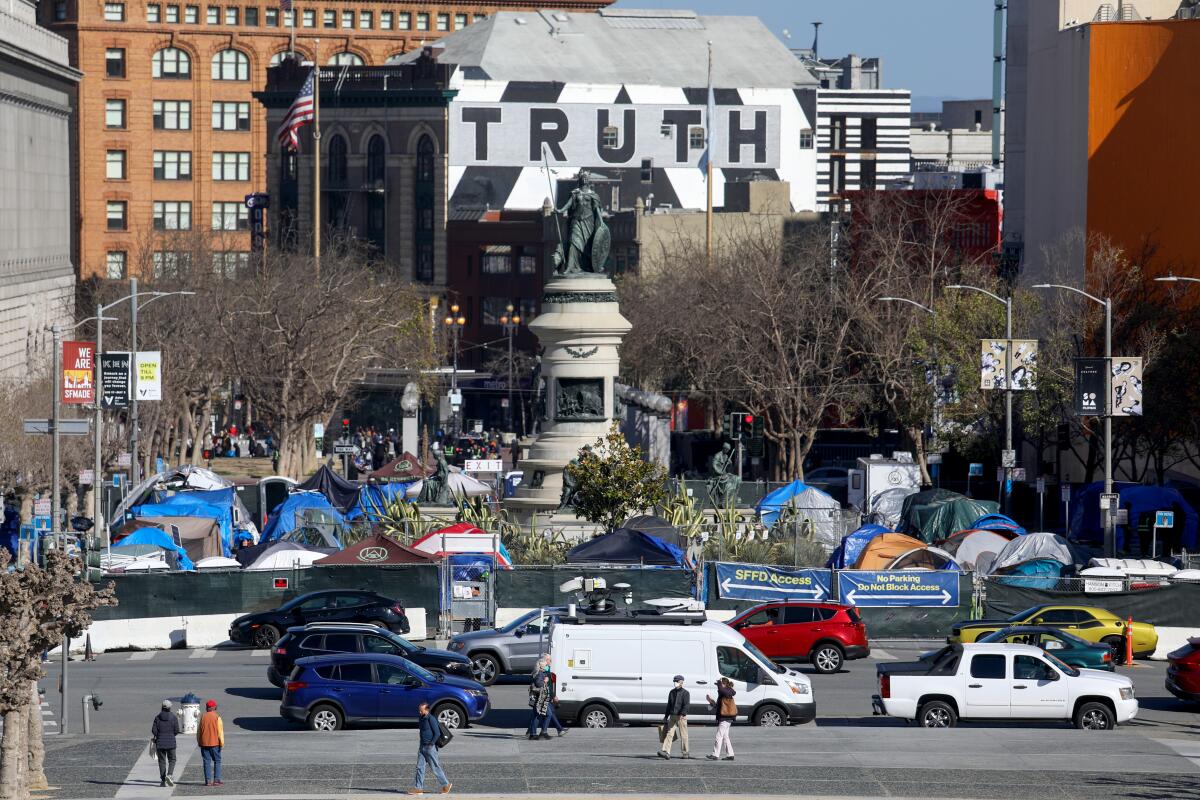 An encampment of blue tents is seen before San Francisco's Pioneer Monument at Civic Center Plaza