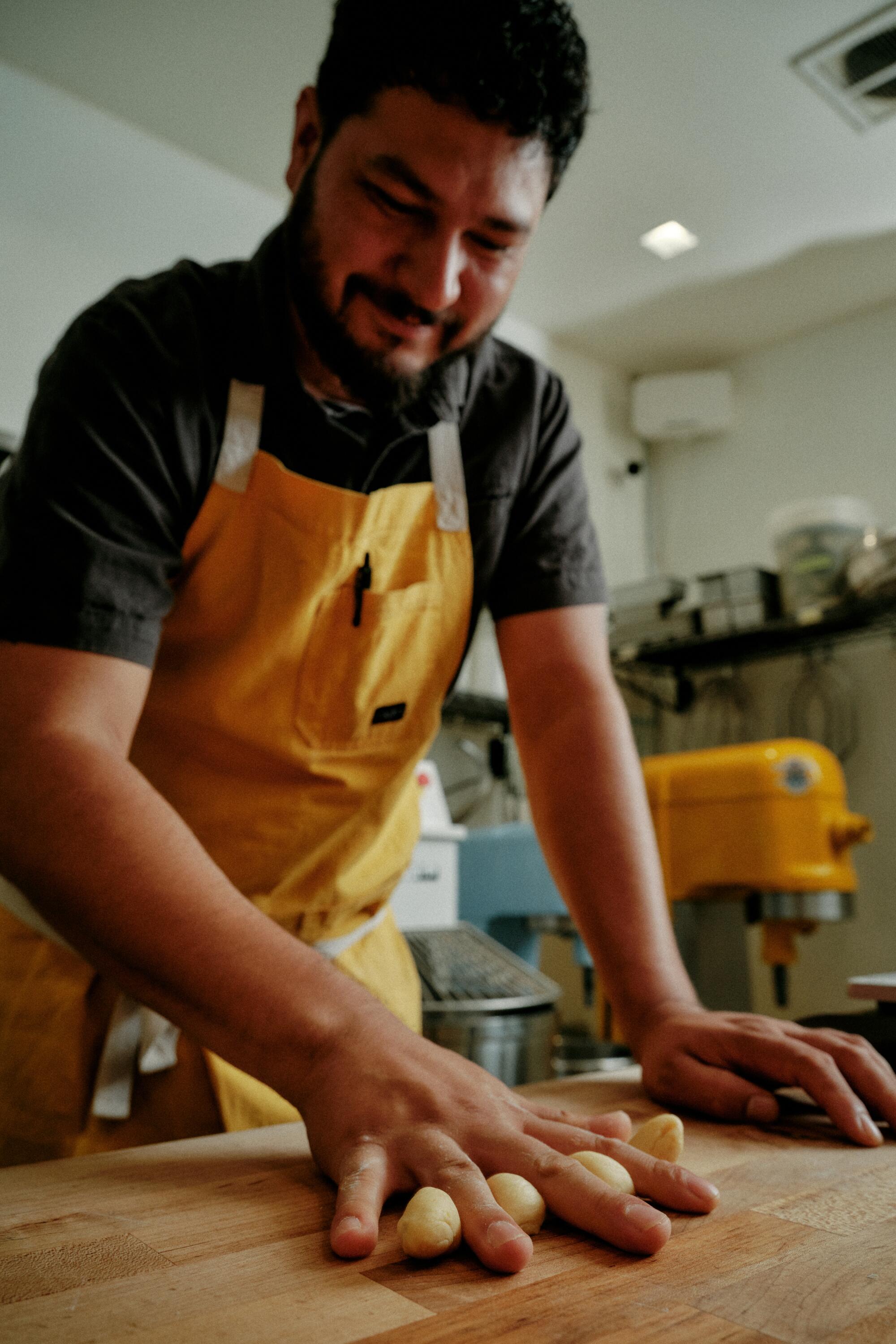 Gusto Bread owner Arturo Enciso rolls dough into a log and then again into balls meant to look like bones for pan de muerto.