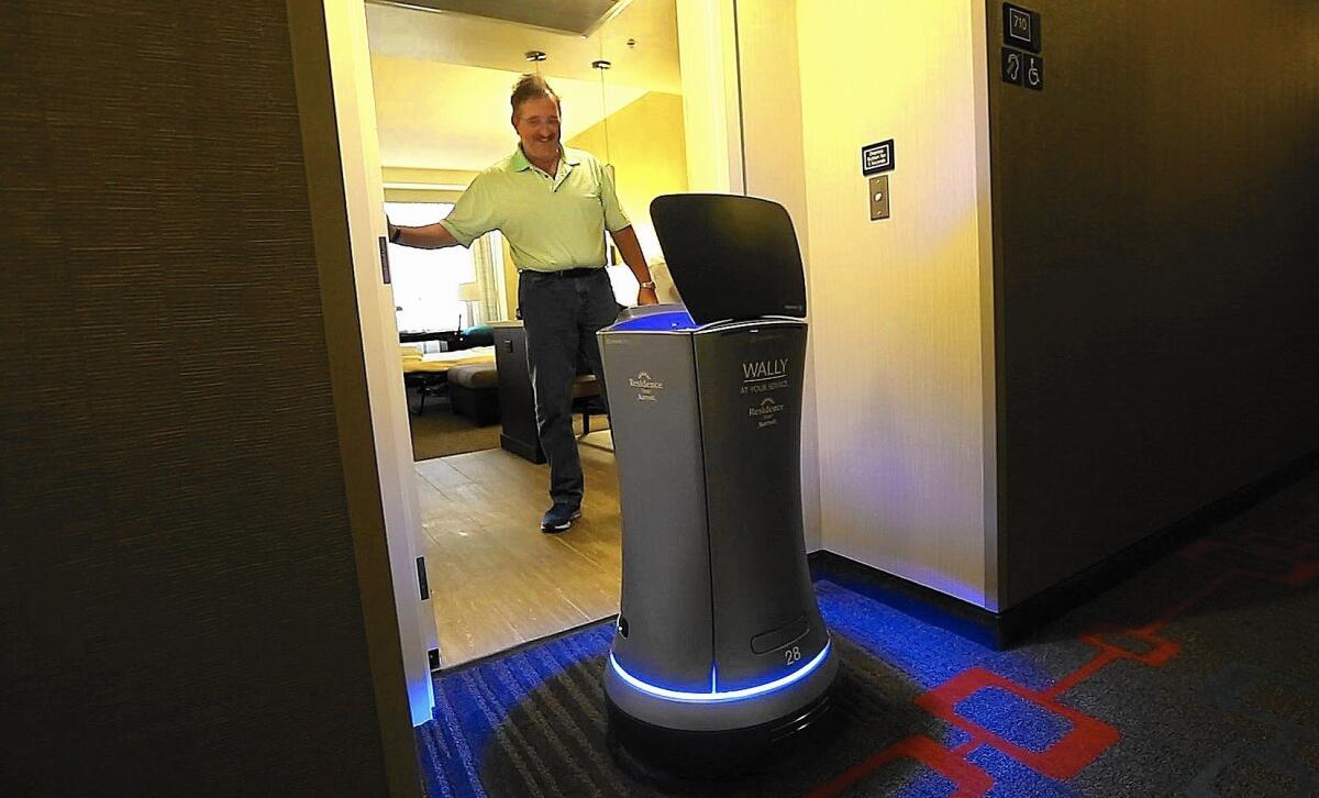 William Savoie of Burlington, Vt., opens the door for Wally, a robot bellhop, as it delivers his order of two bottles of water to his room at the Residence Inn by Marriott on Century Boulevard in Los Angeles. The robot can deliver smaller items such as towels, snacks and coffee to hotel guests.