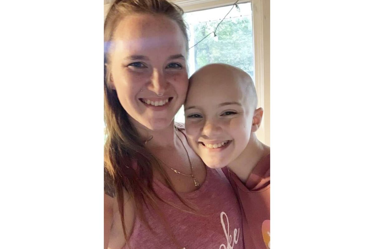 In this photo provided by the family, Rio Allred, 12, stands with her mother, Nicole Ball, a few minutes after she asked her parents to shave her head in September 2021 at their Elkhart, Ind. home. The suicide of 12-year-old Rio in March 2022, left her close-knit family reeling and wondering if they'd missed any signs. They knew she was bothered by merciless bullying about her alopecia, an autoimmune disease that causes hair loss. The family complained to school authorities and gave Rio a choice of transferring or home-schooling, but she wanted to stay put, Ball says. "She put on such a brave face. … I never thought it would get to this point." (Nicole Ball via AP)