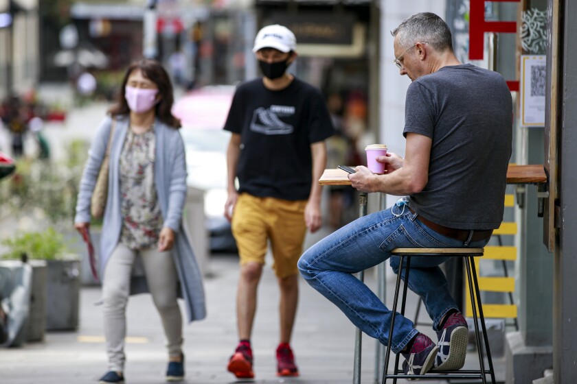 A man sits outside a cafe in central Auckland, New Zealand, Friday, Dec.3, 2021. Bars, restaurants and gyms reopened in Auckland on Friday as the last major parts of a lockdown that lasted more than 100 days ended. New Zealand has begun a new phase in its virus response in which there won't be lockdowns but people will be required to show vaccine passes for many services. (Alex Burton/NZ Herald via AP)