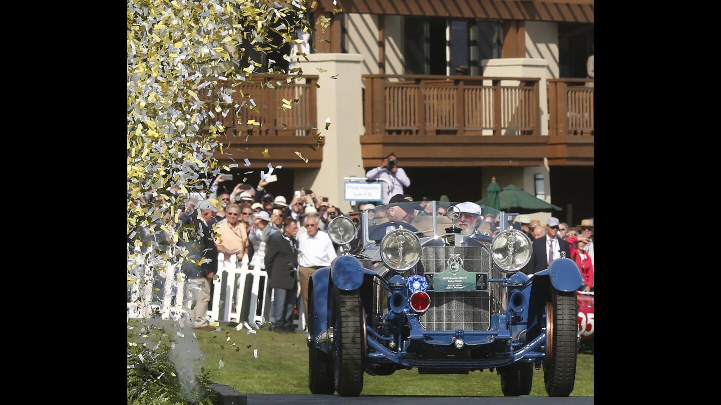 Confetti flies into the air as Bruce McCaw, right, of Bellevue, Wash., is driven over the stage in his 1929 Mercedes-Benz S Barker Tourer by restorer Steve Babinsky after winning Best of Show.