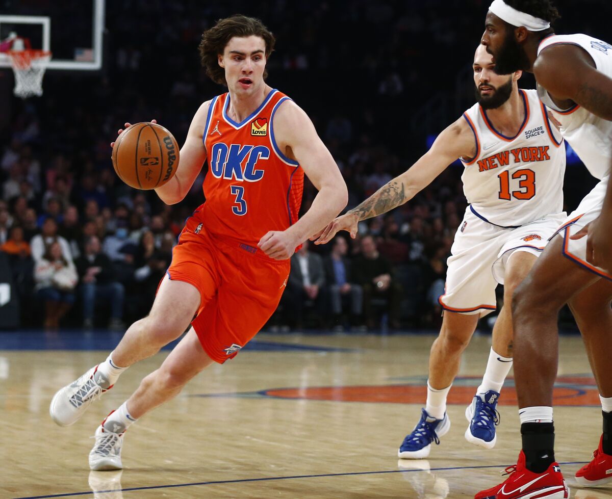 Oklahoma City Thunder's Josh Giddey (3) drives to the basket while defended by New York Knicks' Evan Fournier (13) and Mitchell Robinson, right, during the first half of an NBA basketball game Monday, Feb. 14, 2022, in New York. (AP Photo/John Munson)