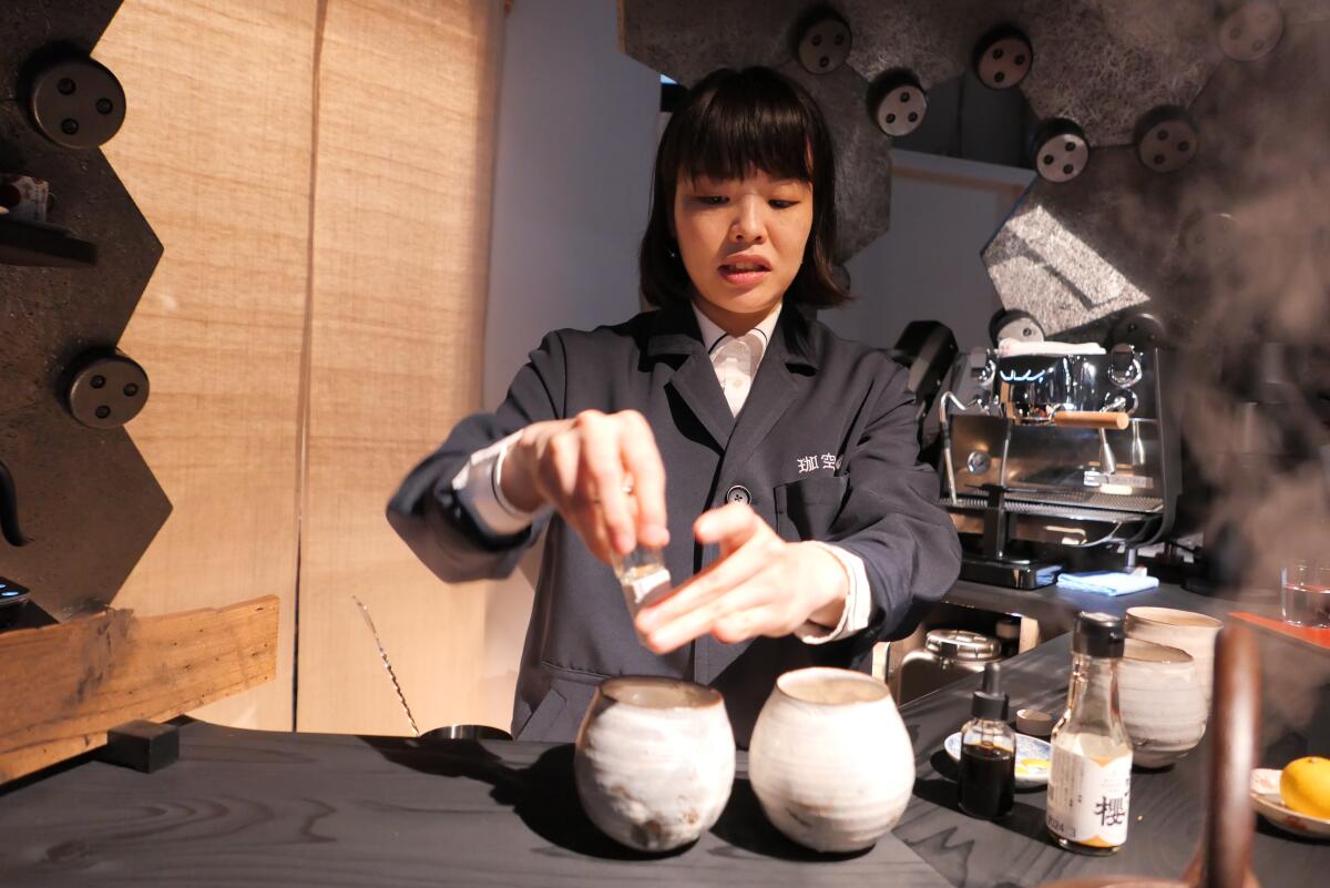 A woman pours something into two white globes on a counter.
