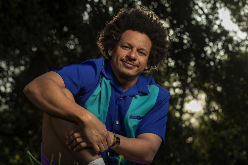 Eric Andre wearing a collared shirt posing in front of trees