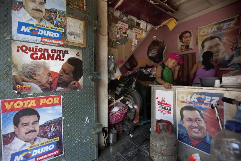 A boy stands inside his family's food stand in Caracas, which is adorned with campaign election posters for acting President Nicolas Maduro.