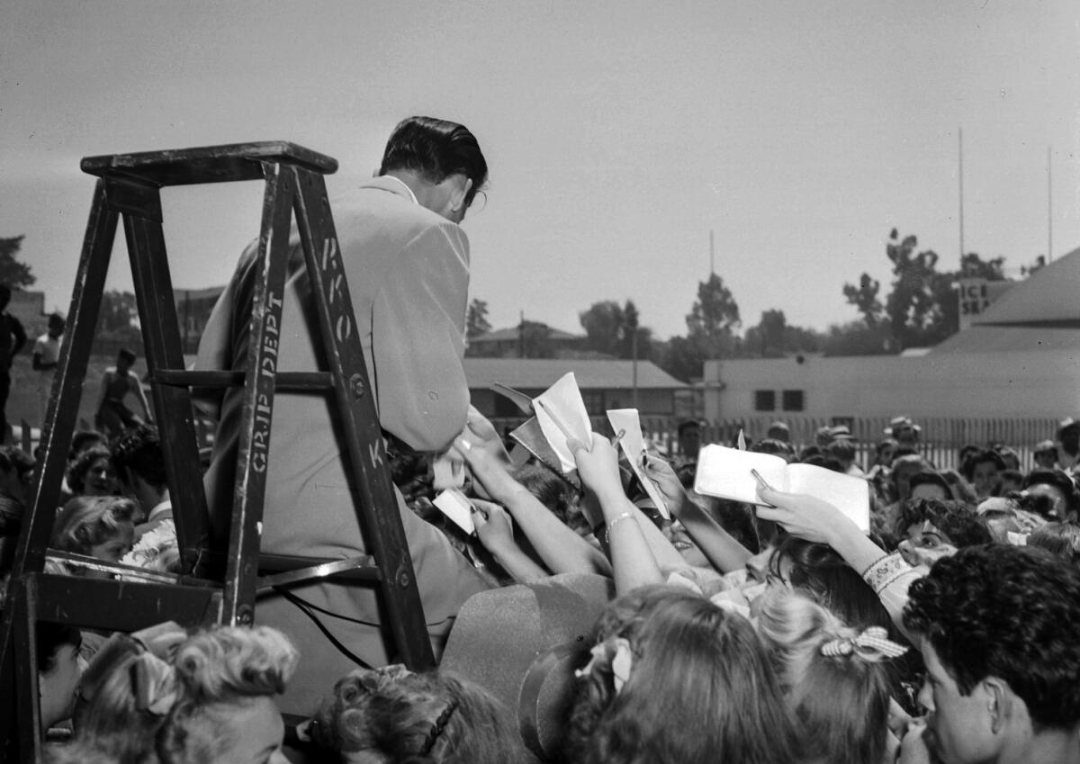 Aug. 11, 1943: Frank Sinatra retreats to a ladder as autograph hounds besiege him following his arrival in Pasadena.