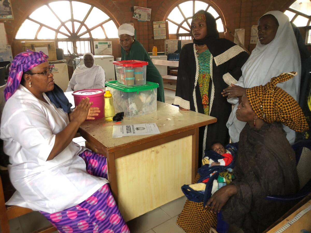 Nutritionist Salamatu Jibril, left, talks to a woman, seated at right, who runs an orphanage in Kaduna, Nigeria. The woman had rushed a 1-month-old weighing under 6 pounds to Barau Dikko Teaching Hospital.