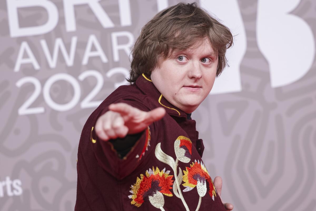 In a head-and-shoulders frame Lewis Capaldi, wearing an embroidered shirt, poses for photographers 