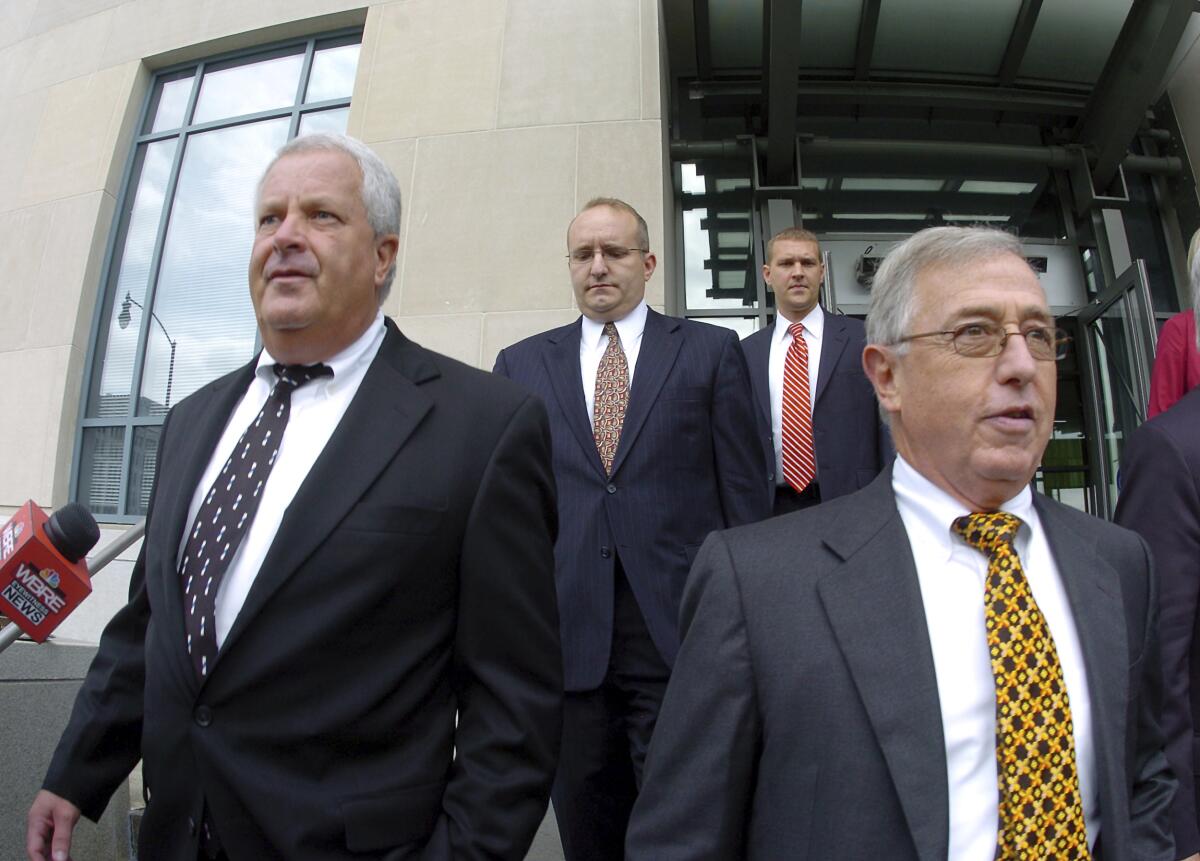 Men in suits and ties exit a courthouse.
