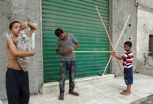 Children build a kite on a street in the Sayida Aisha area of Old Cairo. "It is the tradition in poor neighborhoods. You get together and fly kites" for fun, says one enthusiast.