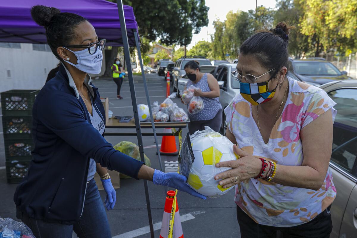 Renata Simril, of LA84 Foundation, distributes sports goods to underserved kids at LAUSD Grab and Go meal center at Thomas Alva Edison School on Wednesday in Los Angeles.
