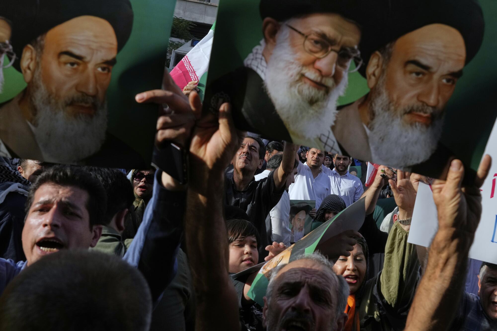 Protesters shouting and holding pictures of bearded men