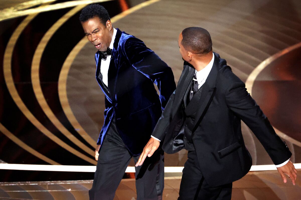 A man reacts to an attack onstage by another man during an awards show.