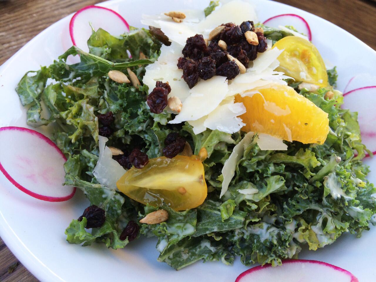 The kale salad features lemon tahini dressing, Parmesan cheese, sunflower seeds, tomato, orange segments and currants.