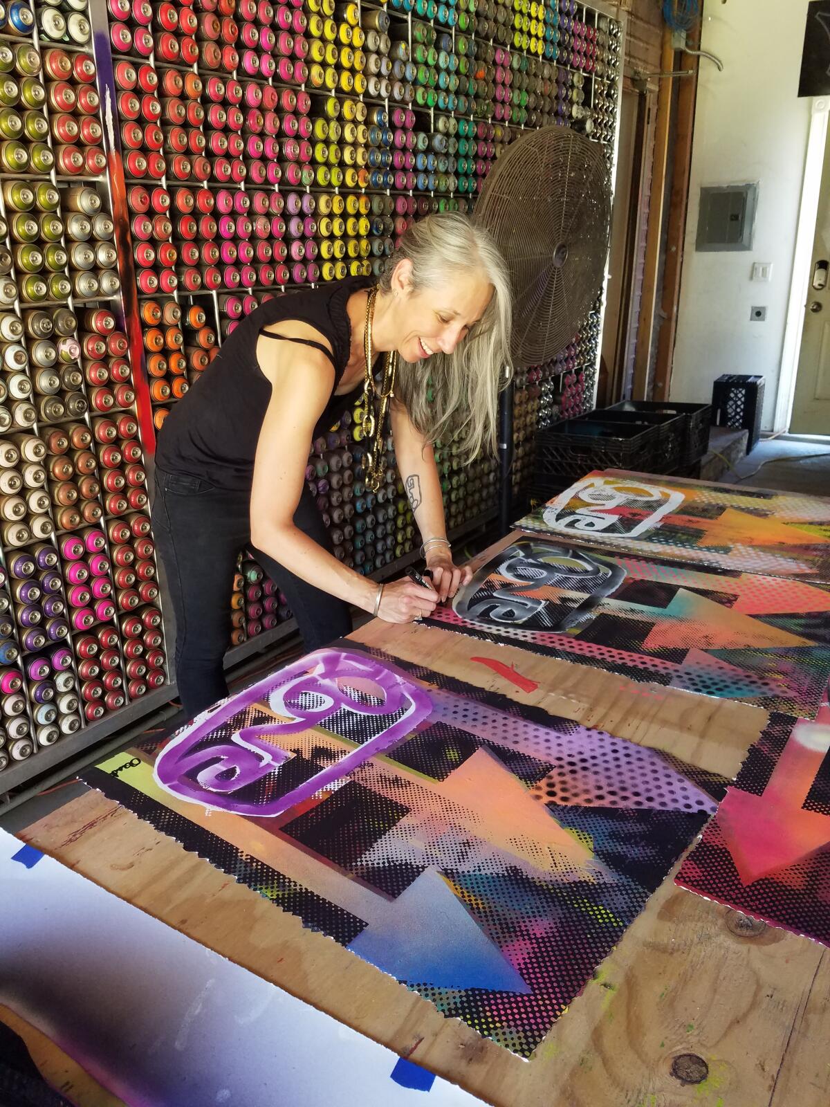 A woman signs colorful artwork 