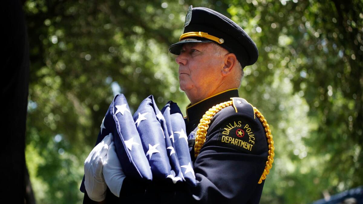 A Dallas police officer carries flags during burial services for Senior Cpl. Lorne Ahrens in July 2016. Ahrens was one of five law enforcement officers killed in an ambush.