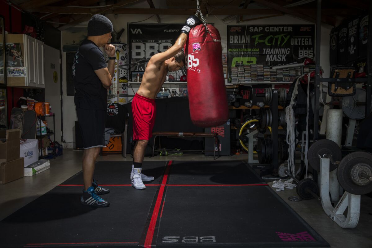 Brian "T-City" Ortega, a UFC featherweight fighter, trains in the garage of his coach, James Luhrsen, left.