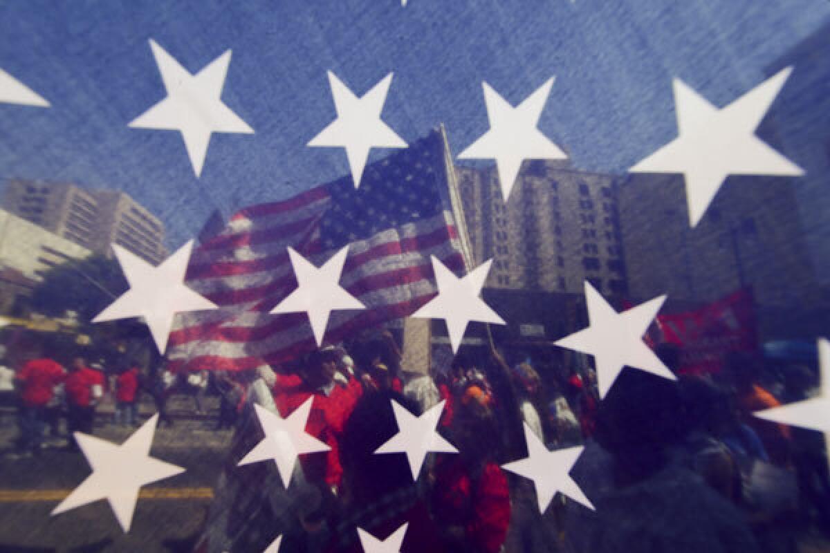 Marchers are visible through a United States flag during a May Day rally in downtown Los Angeles.