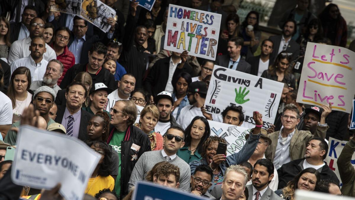 People at the rally hold signs in support of the homeless.