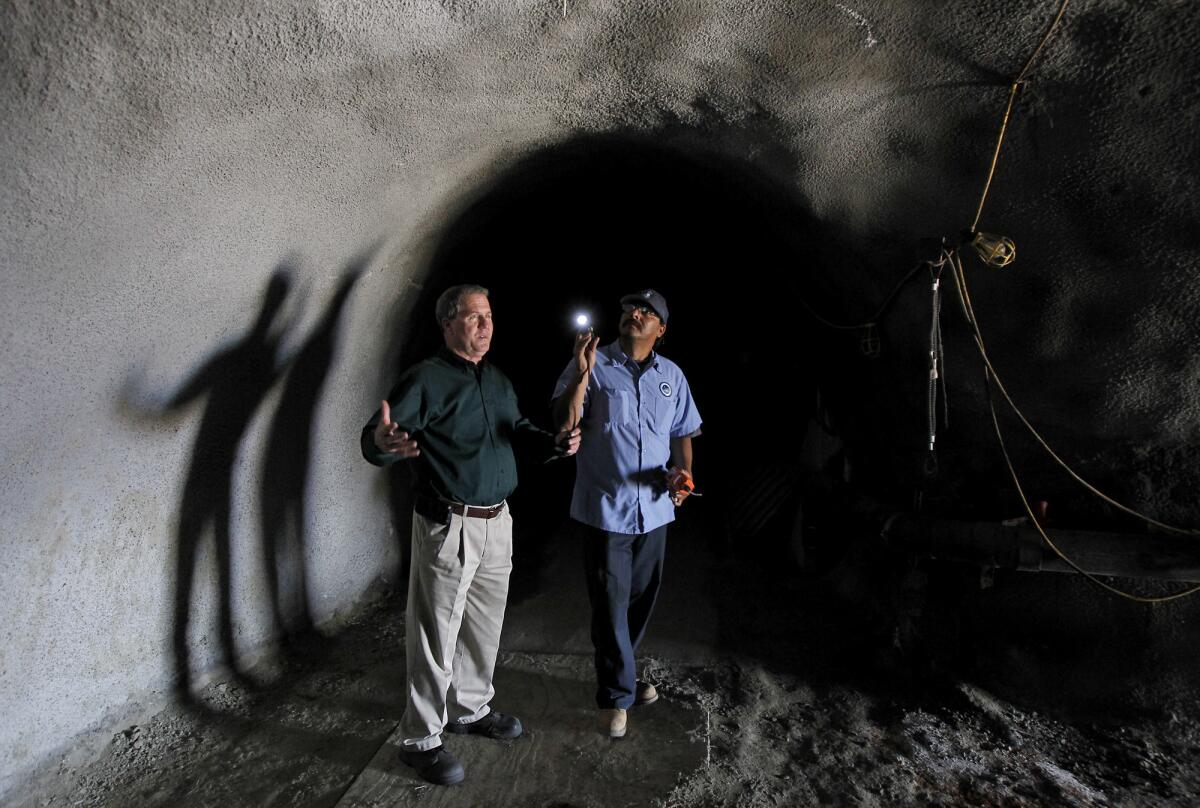 In this 2013 photo, Joe McDivitt, left, and Jimmy Gomez of the South Coast Water District stand in a 2-mile stretch of sewer tunnel in South Laguna that the district plans to start repairing in late January.