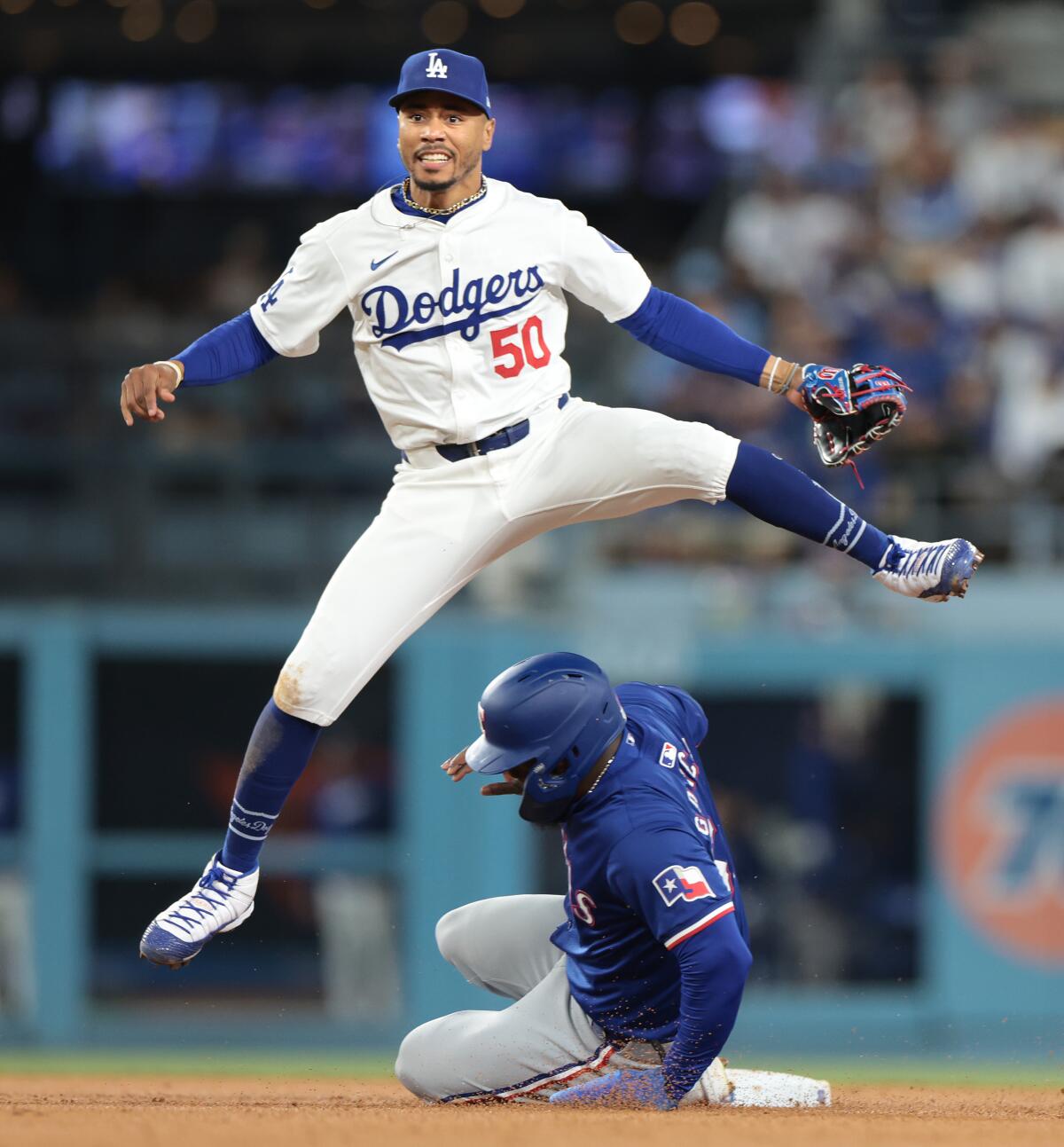 Dodgers shortstop Mookie Betts leaps over Rangers baserunner Adolis Garcia to complete a double play.