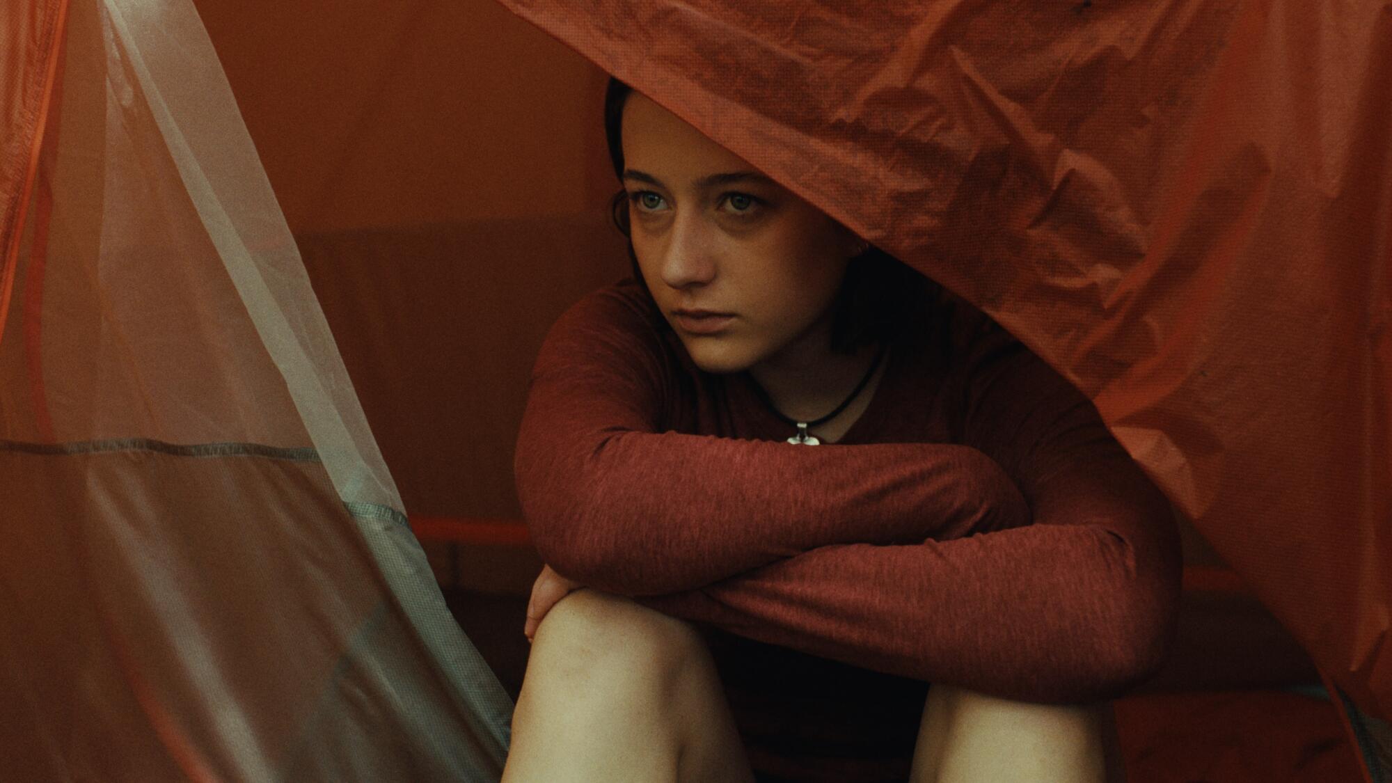 A young woman sits in a tent.