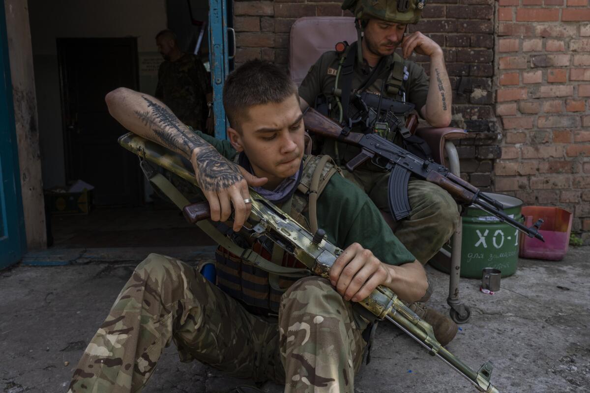 Un miembro de seguridad de un equipo de rescate médico limpia su arma en la región de Donetsk, 