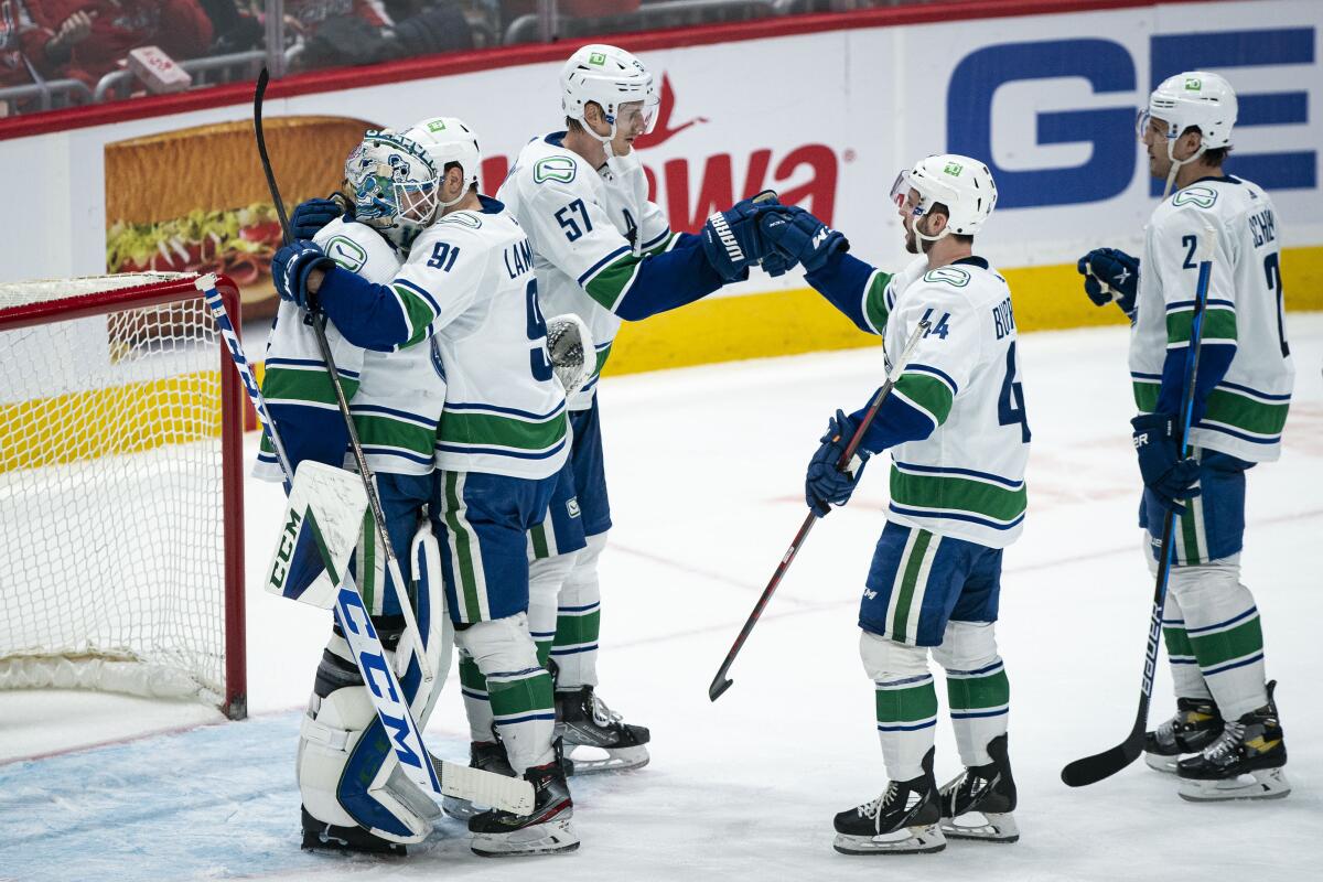 Vancouver Canucks defenseman Tyler Myers (57) fist-bumps defenseman Kyle Burroughs (44) at the conclusion of an NHL hockey game against the Washington Capitals, Sunday, Jan. 16, 2022, in Washington. (AP Photo/Al Drago)
