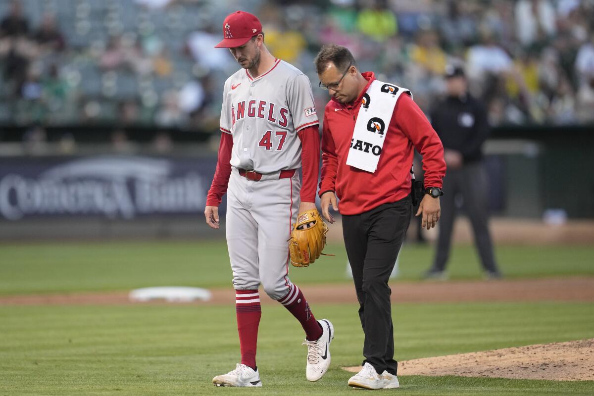 Angels pitcher Griffin Canning walks off the field with a team trainer after being relieved in the fourth inning.