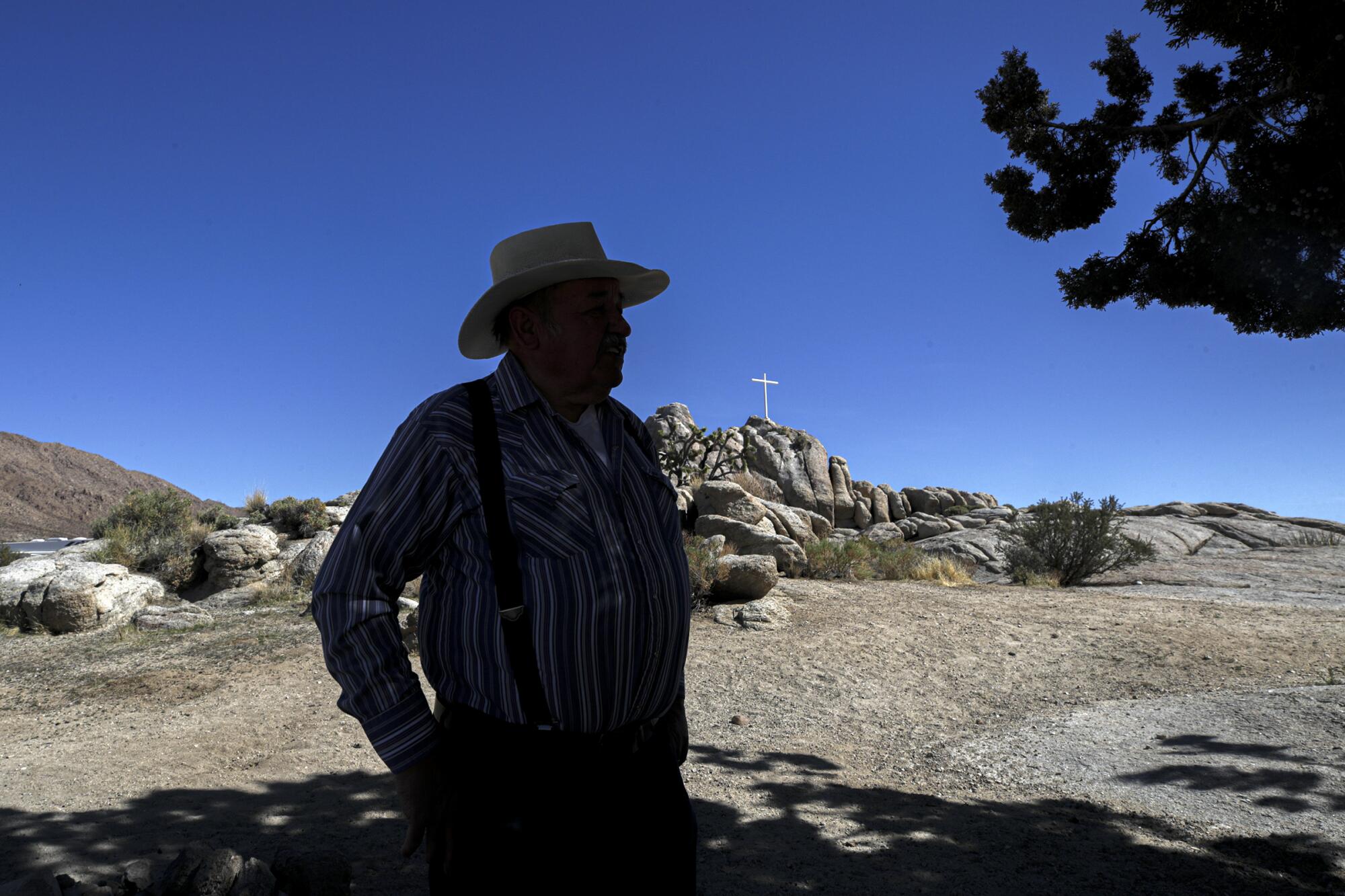 A man stands in the shade of a juniper tree in the desert