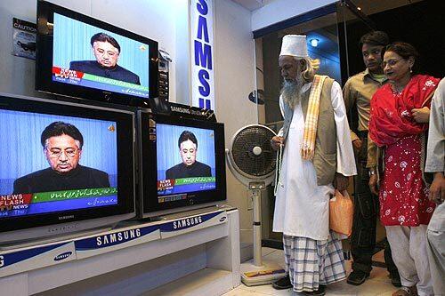 Viewers at an electronics shop in Karachi, Pakistan, watch President Pervez Musharraf give a speech in which he promised to lift the nation's emergency decree by Dec. 16.