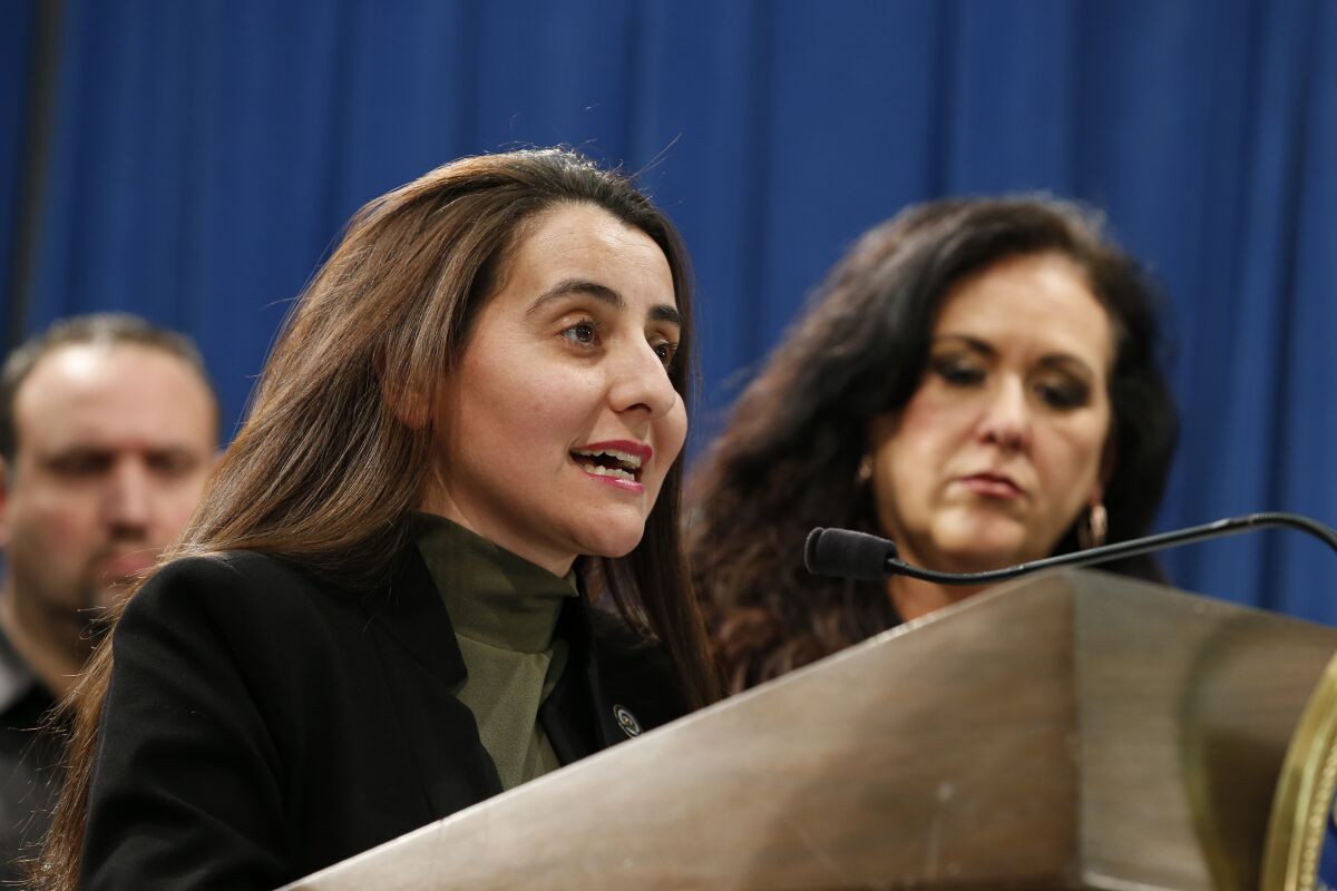 A woman speaks into a microphone on a lectern.