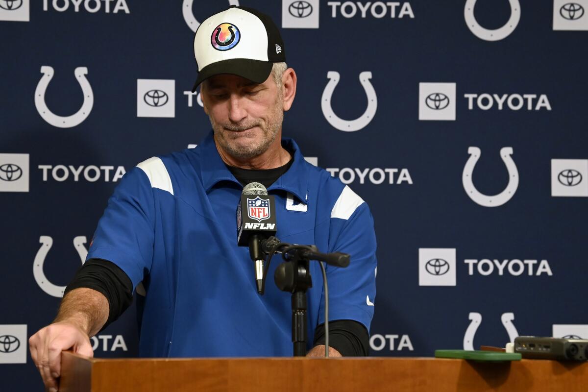 Frank Reich sits at a table while speaking into a microphone