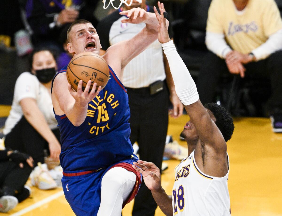 Nuggets center Nikola Jokic, left, attempts a reverse layup against Lakers forward Rui Hachimura.