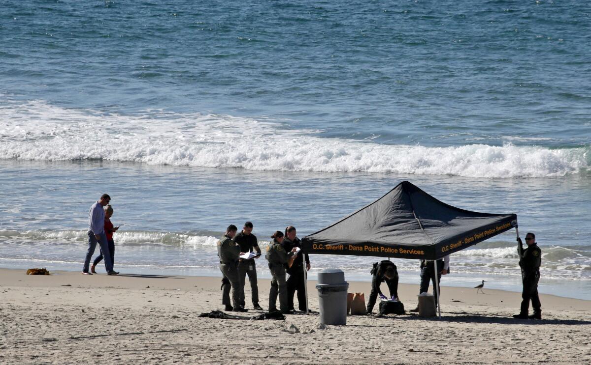 Law enforcement officers work under a tent on a beach.
