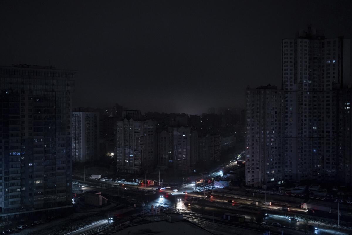Cars drive past dark residential blocks after a Russian rocket attack in Kyiv.