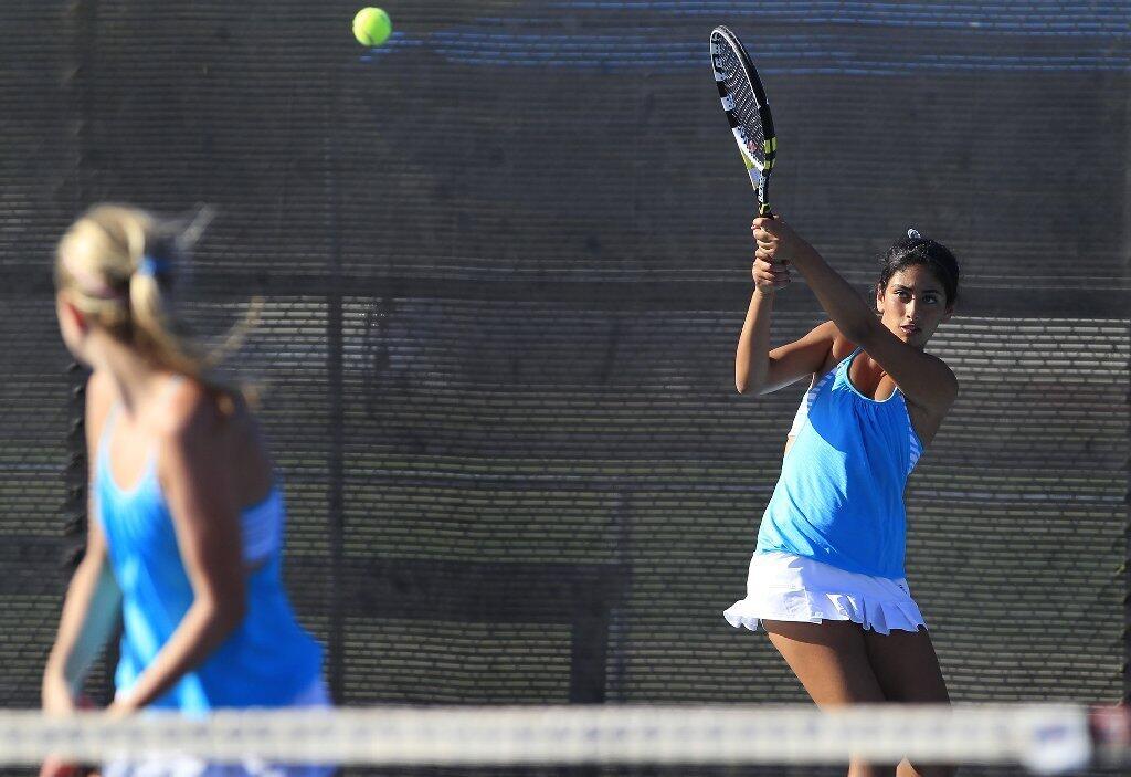 Corona del Mar High's Kimmia Naaseh, right, follows through with her swing, as partner Kenzie Purcifull, left, looks on during a doubles match against Peninsula on Wednesday.