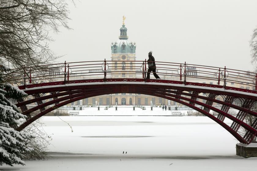 A woman walks over a bridge on the snow-covered palace grounds of Charlottenburg Palace in Berlin, Germany, Friday, Dec. 3, 2010. (AP Photo/Gero Breloer)