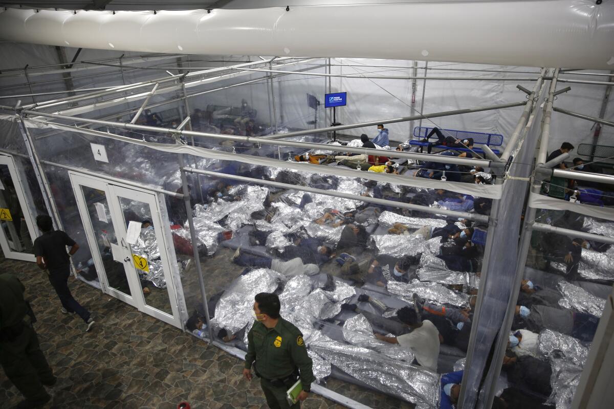 FILE - In this March 30, 2021, file photo, minors are shown inside a pod at the Donna Department of Homeland Security holding facility, the main detention center for unaccompanied children in the Rio Grande Valley run by U.S. Customs and Border Protection (CBP), in Donna, Texas. A federal volunteer at the Biden administration's largest shelter for unaccompanied immigrant children says paramedics were called regularly during her the two weeks she worked there. She said panic attacks would occur often after some of the children were taken away to be reunited with their families, dashing the hopes of those left behind. The conditions described by the volunteer highlight the stress of children who cross the U.S.-Mexico border alone and now find themselves held at unlicensed mass-scale facilities waiting to reunite with relatives. (AP Photo/Dario Lopez-Mills, Pool,File)