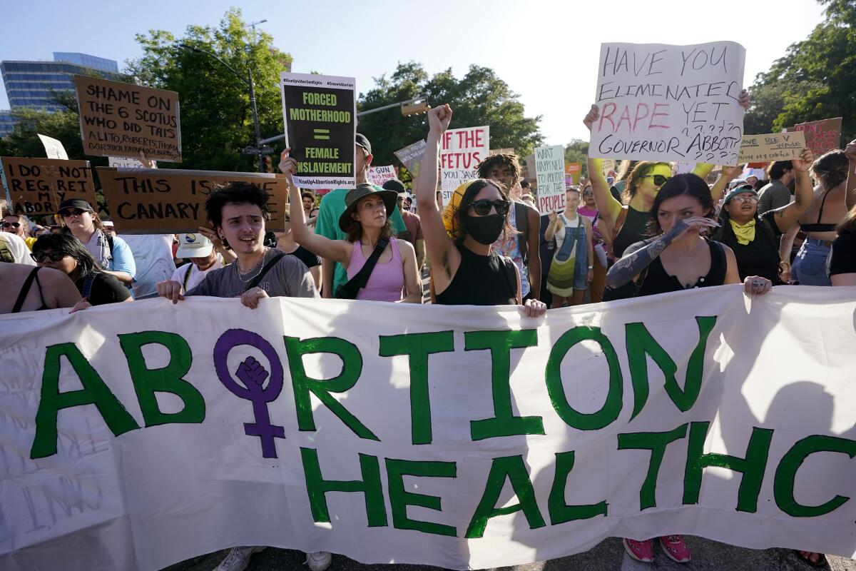 People hold up signs and a large banner that says Abortion Health