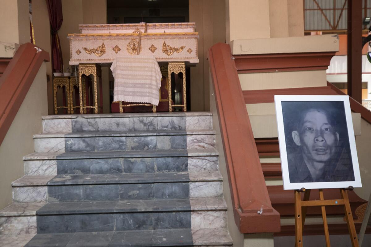 A portrait of the infamous serial killer Si Ouey is displayed below his coffin ahead of the cremation of his remains.