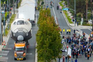 Downey, CA - October 17: A crown washes as movers transport pieces of the Space Shuttle Inspiration, a full-scale mock-up of a space shuttle along Bellflower Blvd. from a Downey Parks and Recreation storage yard for restoration and eventual display in a new exhibit hall at the Columbia Memorial Space Center on Thursday, Oct. 17, 2024 in Downey, CA. (Brian van der Brug / Los Angeles Times)