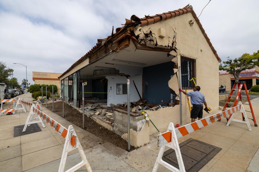 Pasadena, CA - May 14: A worker works on a building destroyed and a memorial grows where three people died and three were severely injured after their Tesla crashed while traveling at speeds of over 100 mph in Pasadena Tuesday, May 14, 2024. (Allen J. Schaben / Los Angeles Times)