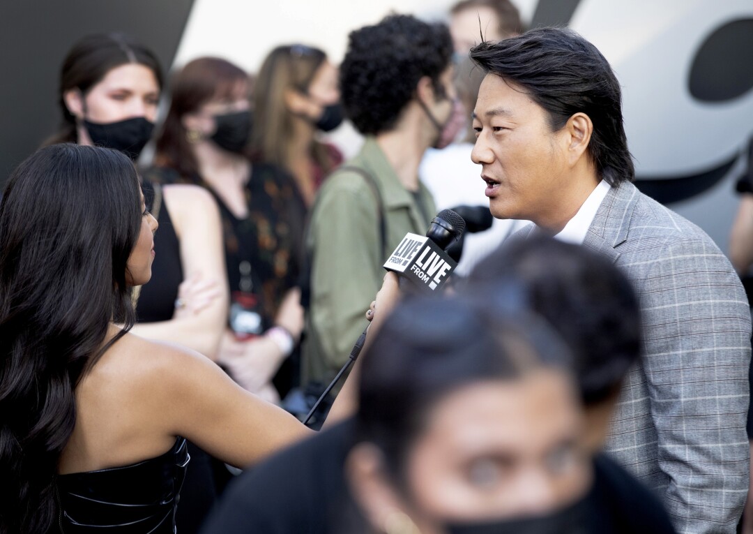 Sung Kang 与一位带麦克风的女士一起采访未戴口罩的抵达者