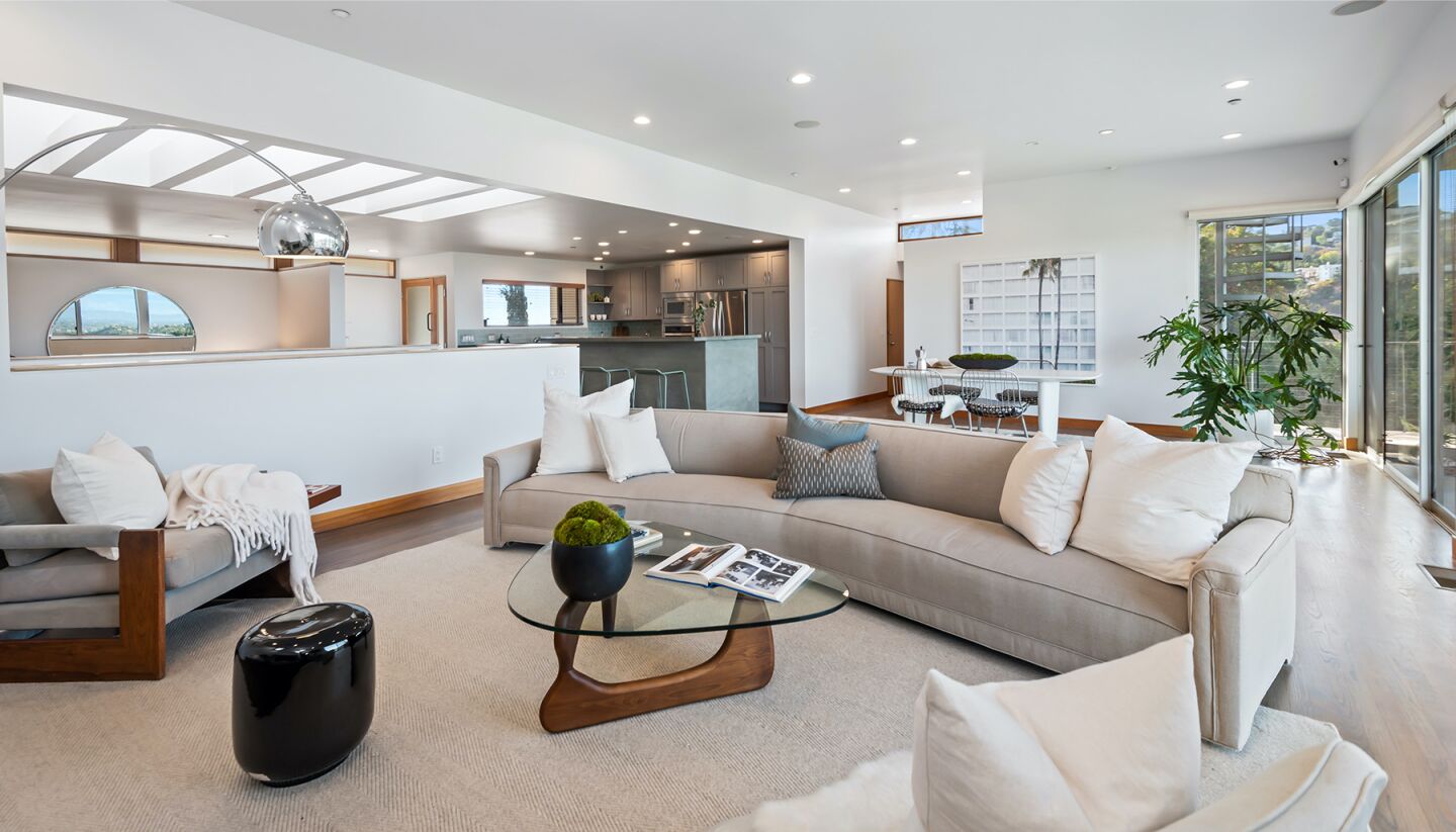 The open floor plan has living room furniture, skylights and white walls.