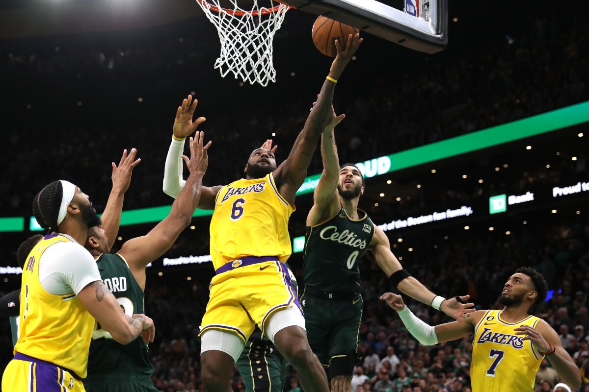 Boston's Jayson Tatum makes contact with LeBron James as the Lakers star puts up a shot.