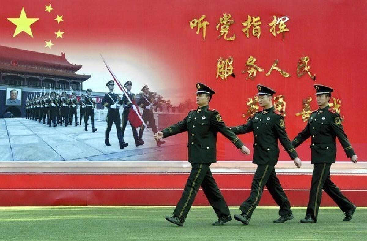Chinese paramilitary police march past a sign that reads, "Serve the party and the people," near the Great Hall of the People in Beijing, where the Communist Party is holding its 18th congress.
